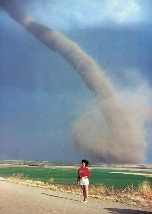 A woman gets her photo taken with a tornado in the background 1989