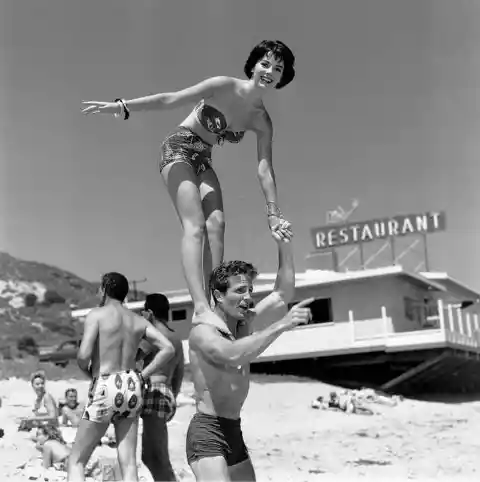 Here's Natalie Wood standing on the shoulders of actor Steve Rowland at the Thalians Beach Ball. (1956)